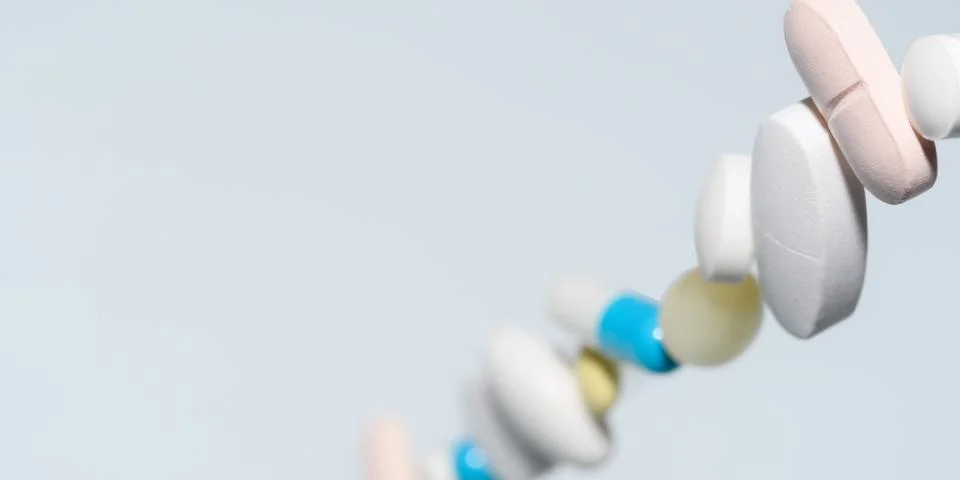 Colorful tablets and capsules float in light blue copy space, clean medical Stock Photos