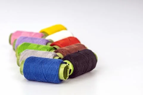 Colorful Thread Spools Arranged in a Diagonal Line on White Background Stock Photos