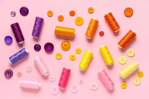 Colorful thread spools with buttons on pink background 写真素材