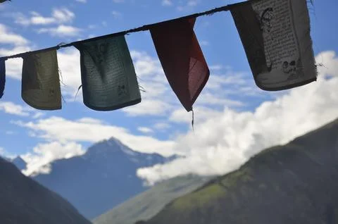 Colorful Tibetan flags with script with the background of mountains and clouds Stock Photos