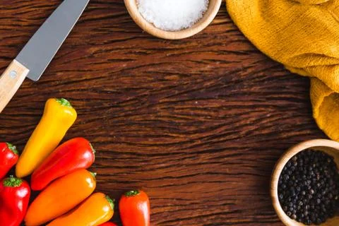 Colorful tiny bell peppers with kitchen utensils on a wood surface Foto stock
