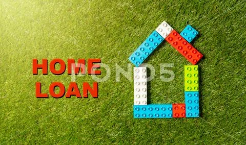Colorful toy blocks house and tex Home Loan written on grass in banking and p Stock Photos