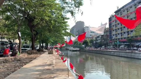 Colorful triangle flag pennant string hang and sway near city canal on sunny day Video stock 172363672