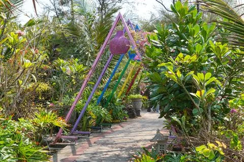 Colorful triangular arch on a paved walkway in a tropical garden. Stock Photos