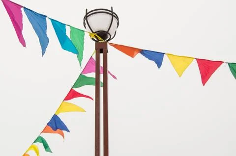 Colorful triangular cloth flags hanging on ropes tied to a lamppost, decorati Stock Photos