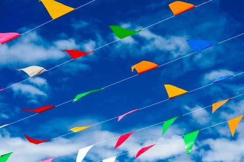 Colorful triangular flag line moving by wind on blue sky white cloud Stock Photos
