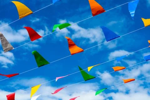 Colorful triangular flag line moving by wind on blue sky white cloud 写真素材