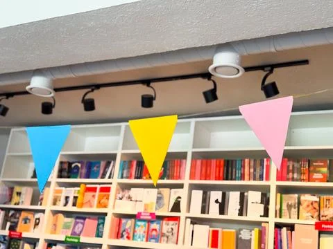 Colorful triangular flags hanging inside bookstore. Festive decoration, cel.. Stock Photos
