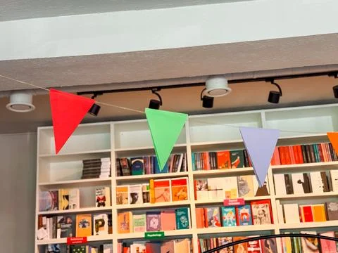 Colorful triangular flags hanging inside bookstore. Festive decoration, cel.. Stock Photos