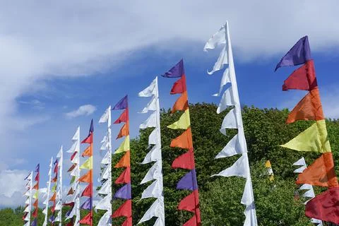 Colorful triangular flags waved in the wind with blue sky and trees in the ba Stock Photos