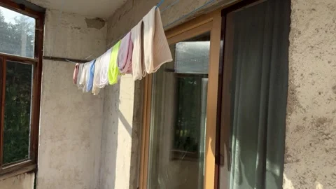 Colorful washed clothes drying on a clothesline on a sunny balcony Stock Footage 341510386
