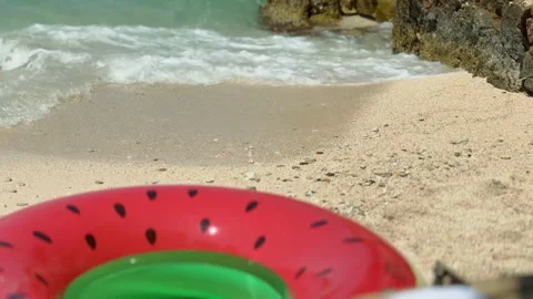 Colorful watermelon-shaped inflatable ring  on a sunny sandy beach near wav.. Stock Footage 338772333