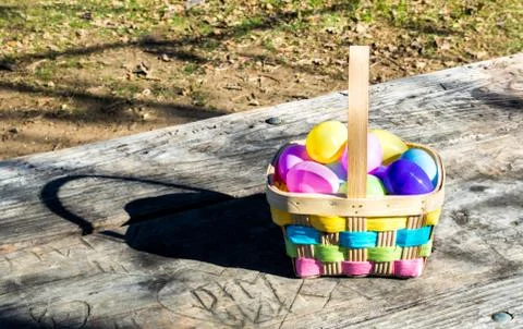 Colorful wicker Easter basket filled with plastic Easter eggs on a wooden table Stock Photos