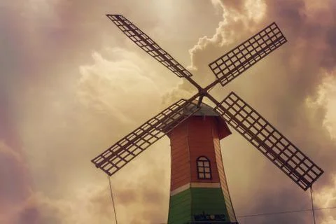 A colorful windmill below a cloudy sky Stock Photos