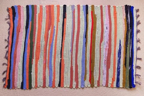 Colorful woven rug with striped pattern on carpeted floor Stock Photos
