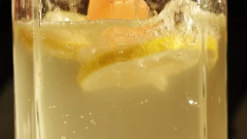 Colorfull ice cubes falling own into soda with sliced lemons preparing lemonade Stock Footage 155792458