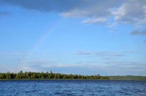 Colorfull rainbow under single cloud over lake Stock Photos