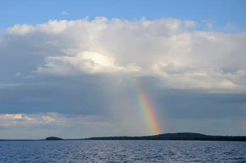 Colorfull rainbow under single cloud over lake Stock Photos