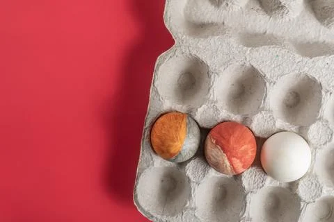 Colorfully painted Easter eggs in a cardboard box on a vibrant red background Stock Photos
