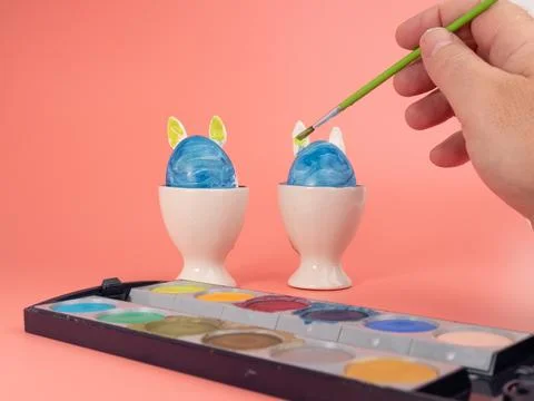 Coloring Easter eggs. Decorate eggs for Easter on a pink background. Stock Photos