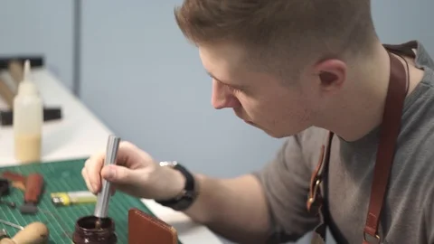 Coloring the ends of a leather wallet. Tanner in the workshop engaged in Stock Footage 104926895