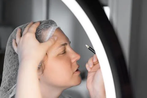 Coloring the eyebrows and eyelashes with henna in a beauty salon. Stock Photos