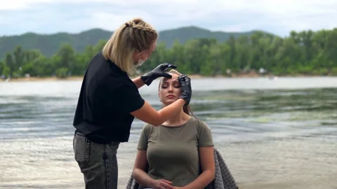 Coloring eyebrows on the banks of the river. Stock Footage 202010039