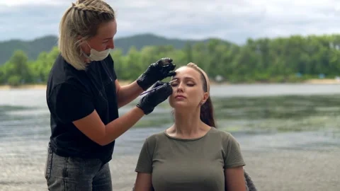 Coloring eyebrows on the banks of the river. Stock Footage 202010372