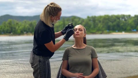 Coloring eyebrows on the banks of the river. Stock Footage 202010389