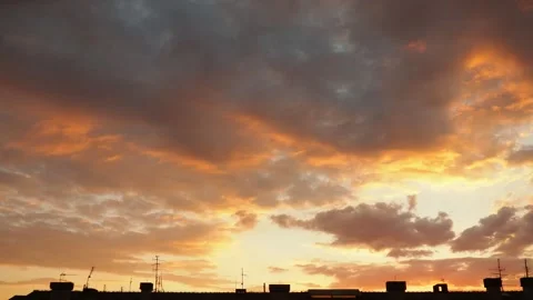 Colors fill the sky as the sun sets over a city. Cloud patterns change as the Stock Footage 335521763