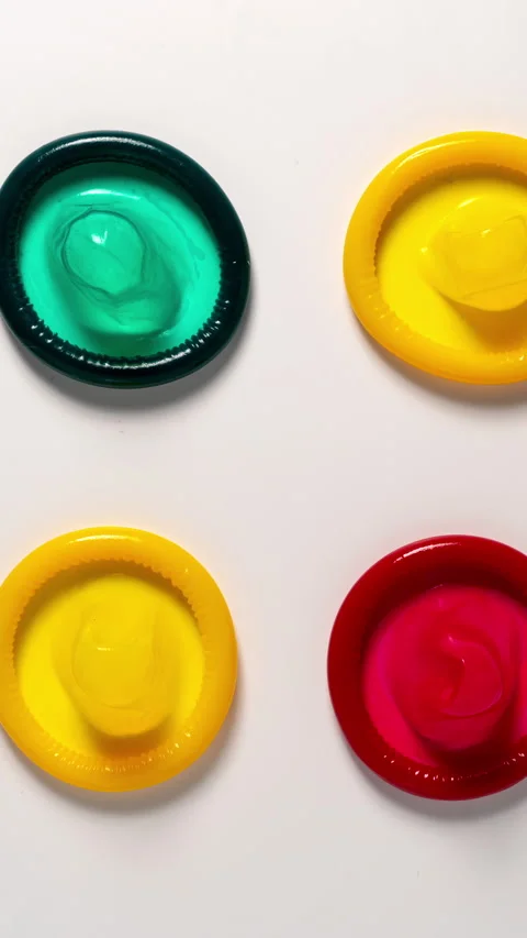 Colour condoms show up on a white table, Stop motion Stock Footage 344860381