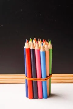 Colour pencils against chalkboard Stock Photos