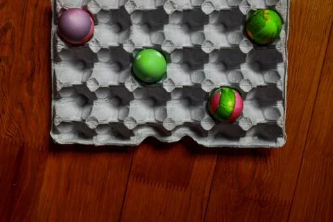 Coloured easter eggs separated in a tray on wooden background Stock Photos