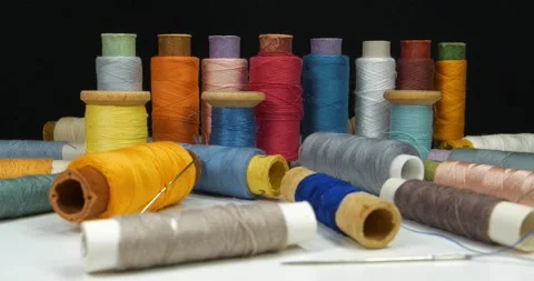 Coloured spools of thread lie on white table on black background Stock Footage 313876743