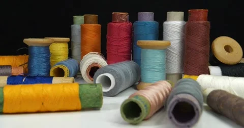 Coloured spools of thread lie on white table on black background,tilt view video Stock Footage 317852010