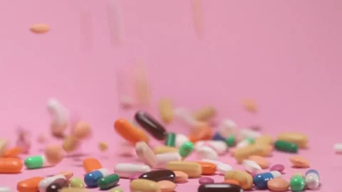 Coloured tablets and pills falling down on pink background Video stock 168173041