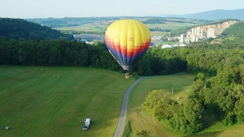 Colourful air hot balloon flying above the green fields and forest. Stock Footage