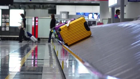 Colourful bags slide on luggage carousel at airport arrival hall, closeup view Stock Footage