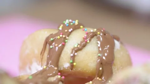 Colourful Candy Balls drop onto chocolate glazed donut Stock Footage 166863314