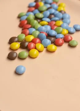 Colourful candy on pink background. Small candies in colored chocolate glaze. Stock Photos