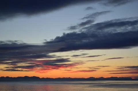 Colourful clouds makes burning dawn sky by the sea shore Stock Photos