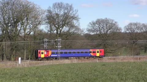 Colourful commuter train travelling through countryside panning Stock Footage 64849745