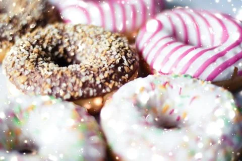 Colourful donuts on marble table with glowing snow, winter holiday food backg Stock Photos