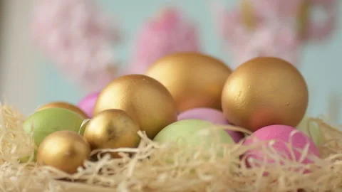 Colourful Easter eggs of pink, golden and green colour lie in straw spinning  Stock Footage 148287468