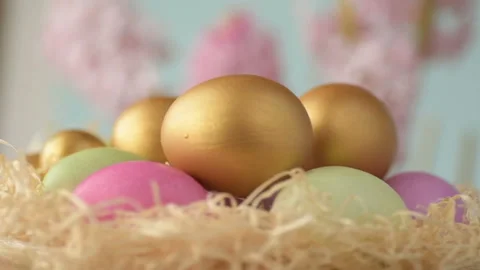 Colourful Easter eggs of pink, golden and green colour lie in straw spinning  Stock Footage 148287484