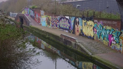 Colourful graffiti is reflected in the rippling waters of Birmingham canal Stock-Footage 72439059