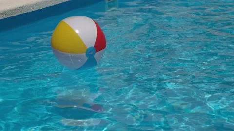 Colourful inflatable beach ball floating in shiny blue swimming pool water Video stock 200779114