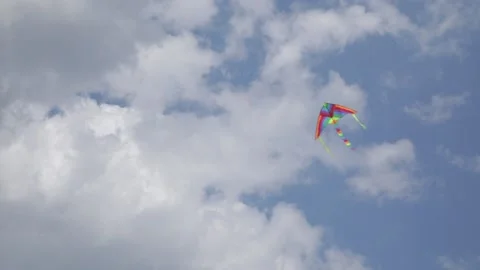 A Colourful Kite Flying Fast in the Clear and Cloudy Sky Stock Footage 219610787