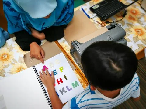 Colourful letters on the book as reference for child to type into the braille Stock-Fotos