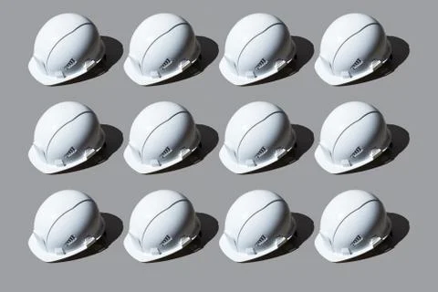 Colourful pattern of white helmets on grey background. View from top. Stock Photos